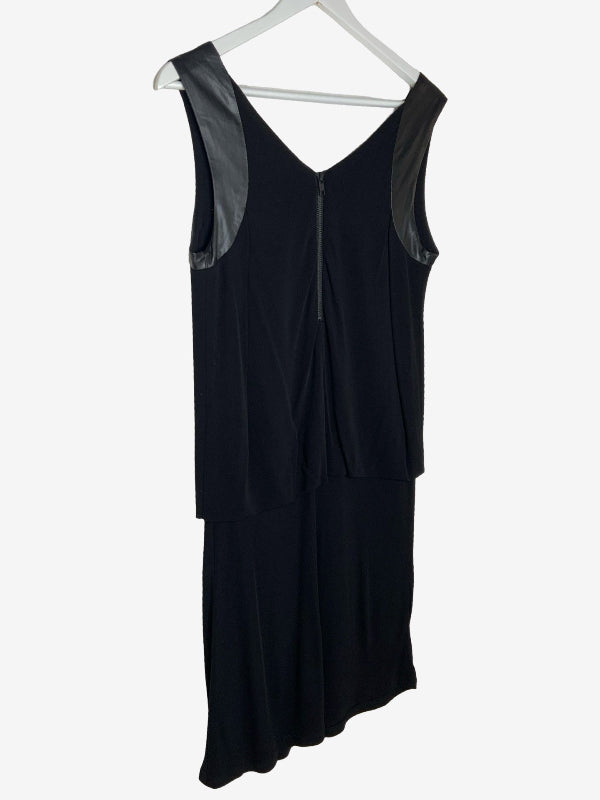 A black sleeveless dress with sheer black mesh shoulder panels and a front zipper, hanging on a white hanger against a light gray background.
