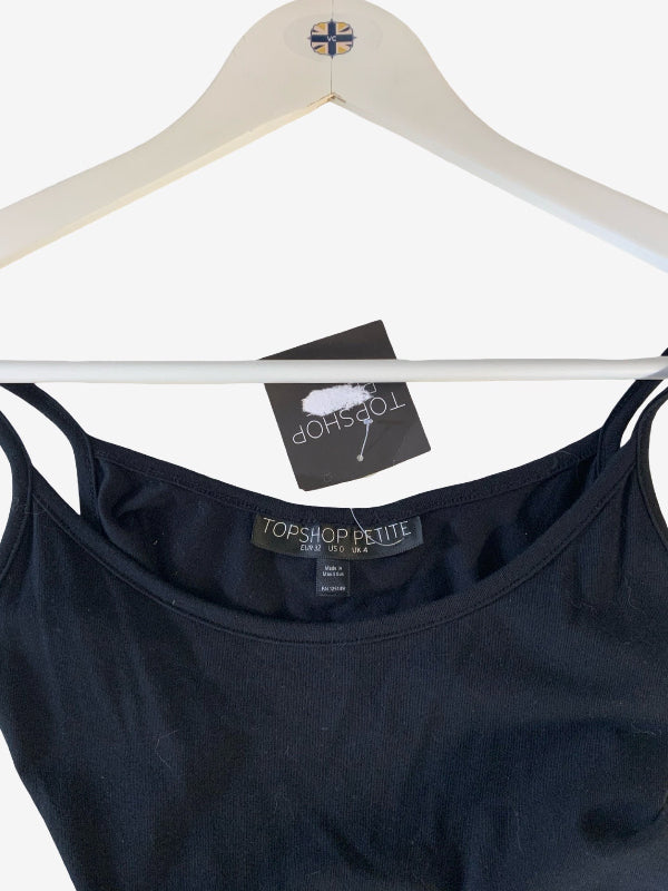 A black spaghetti-strap tank top hanging on a white wooden hanger against a white background, with a Topshop tag and a Topshop Petite size label visible.