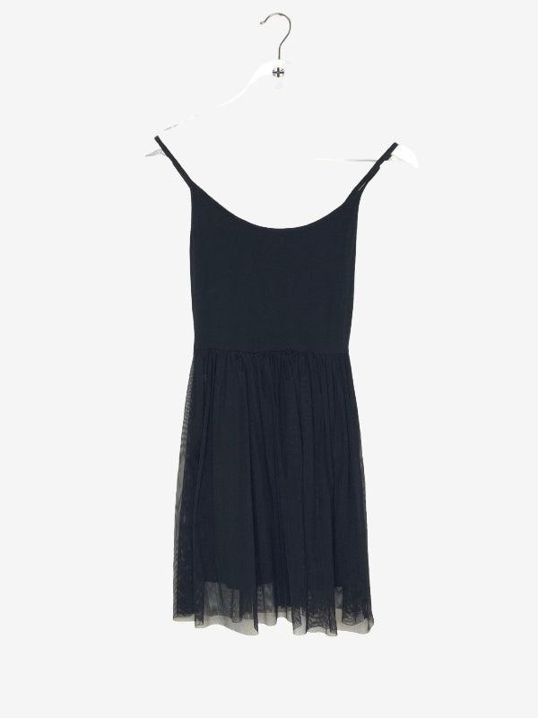 A black sleeveless mini dress with thin shoulder straps and a sheer tulle hem, hanging on a white plastic hanger against a plain white background.