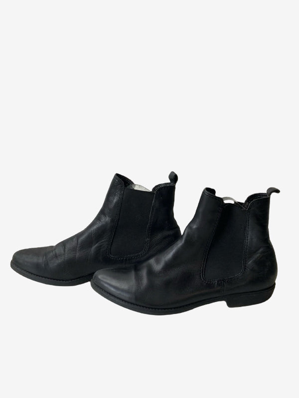 A pair of black leather Chelsea boots with elastic side panels, shown from a three-quarters angle on a light gray background.