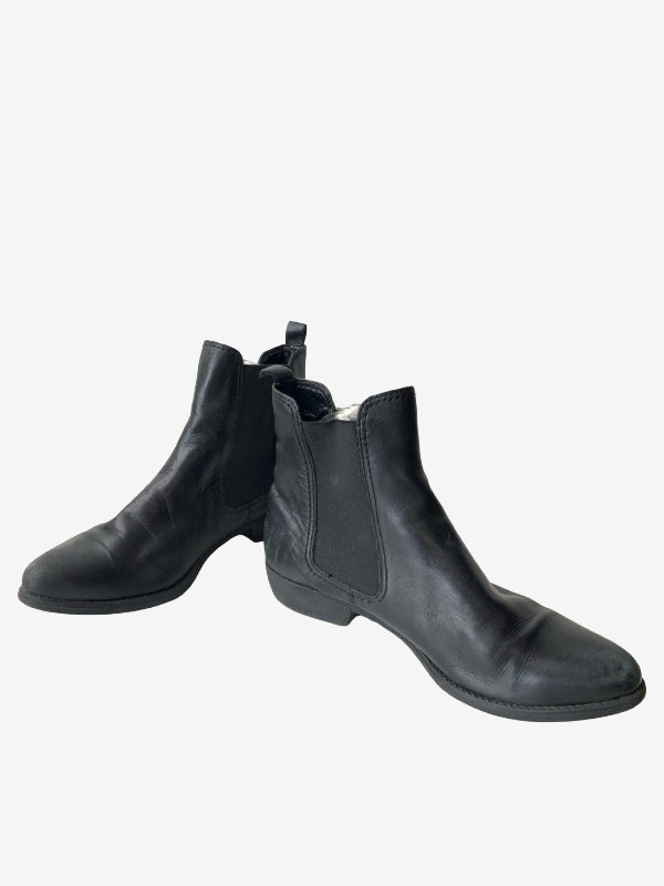 A pair of black leather Chelsea boots with elastic side panels, displayed against a plain light gray background.