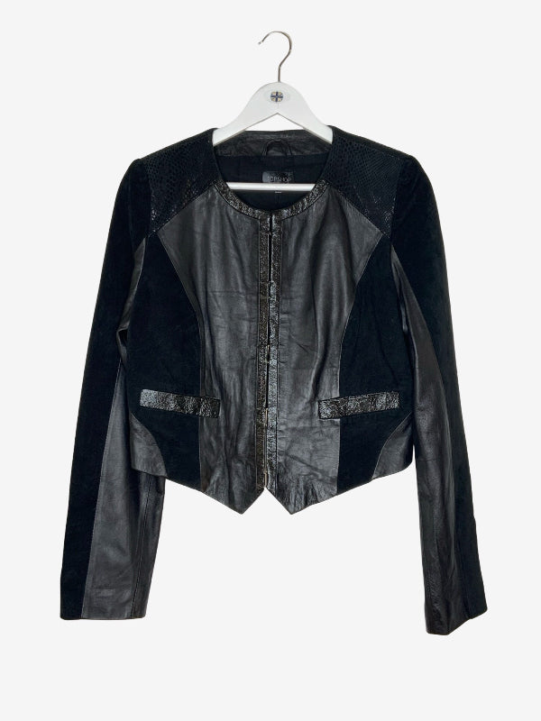 A black long-sleeve jacket with mixed textures, including smooth faux-leather panels, textured mesh shoulder panels, and a central zipper, hanging on a white hanger against a light gray background.