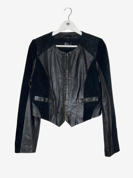 A black long-sleeve jacket with mixed textures, including smooth faux-leather panels, textured mesh shoulder panels, and a central zipper, hanging on a white hanger against a light gray background.