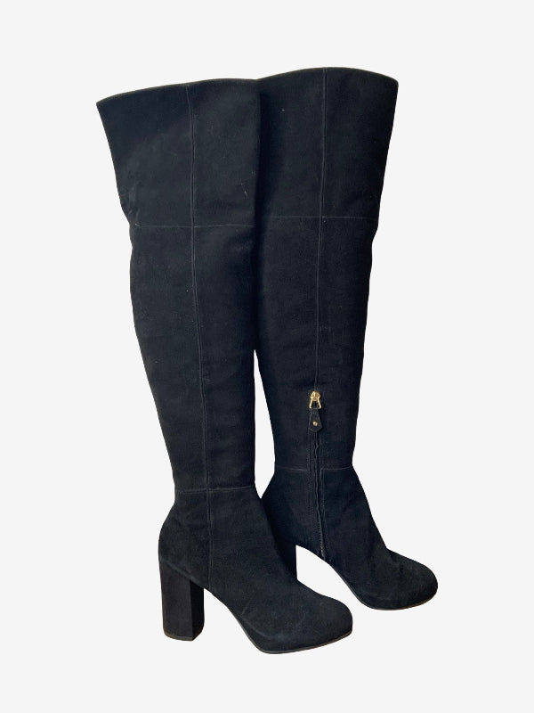 A pair of black faux suede over-the-knee boots with block heels and a small gold zipper pull, shown against a plain light gray background.