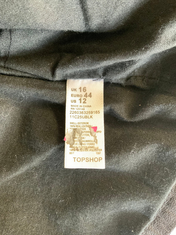 Close-up of a garment's interior label reading TOPSHOP, UK 16, EURO 44, US 12, sewn onto dark gray fabric.
