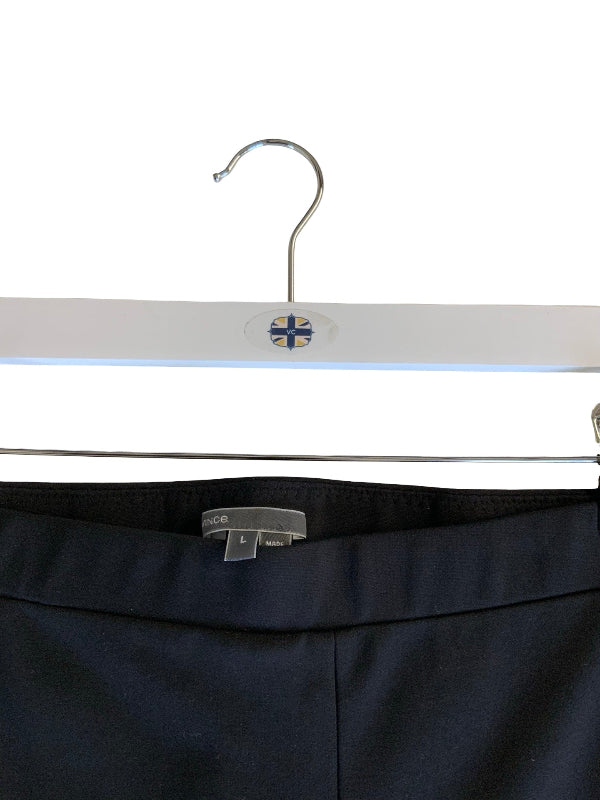 Close-up of black trousers hanging on a white hanger with a small blue and white flag emblem near the hook.