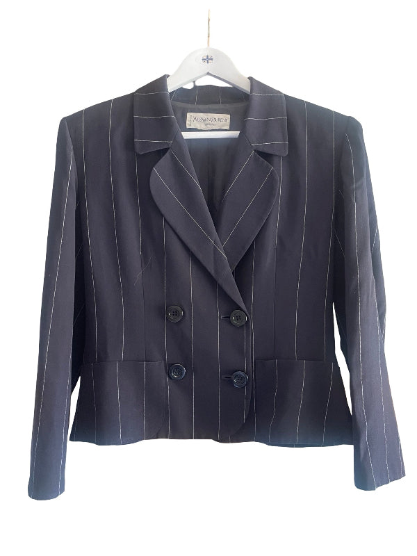 A dark navy blue double-breasted pinstripe blazer with white vertical stripes, hanging on a white hanger against a plain white background.