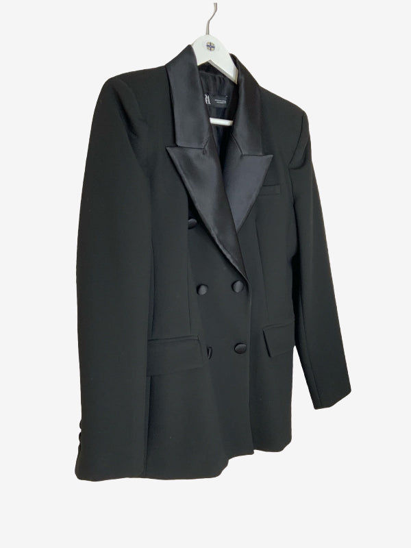 A black double-breasted blazer with satin lapels, hanging on a white hanger against a plain white background.
