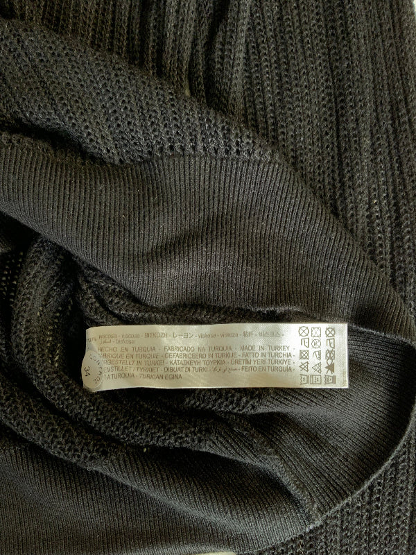 Close-up of a black ribbed knit garment showing the interior neck label and collar construction.