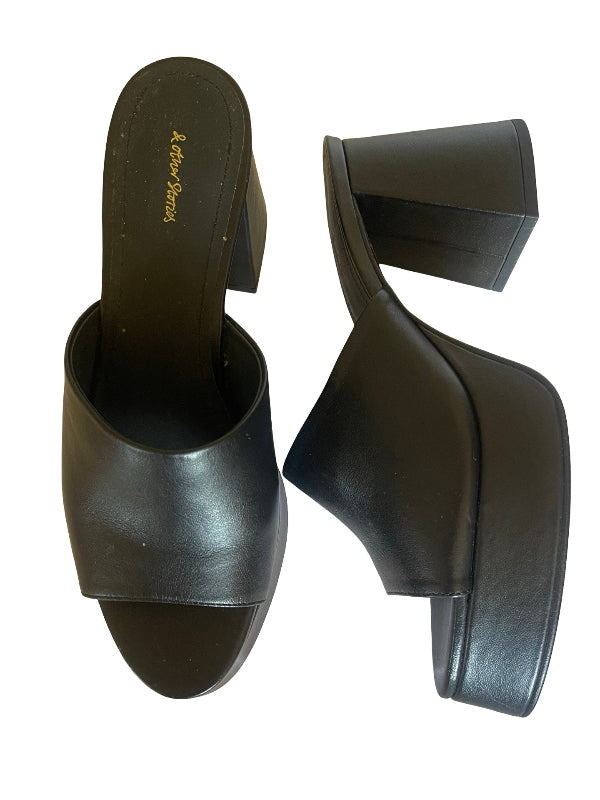 A pair of black leather platform mule sandals with a chunky block heel, shown from two angles on a white background. The insole features the brand name 'and other stories' in gold script.