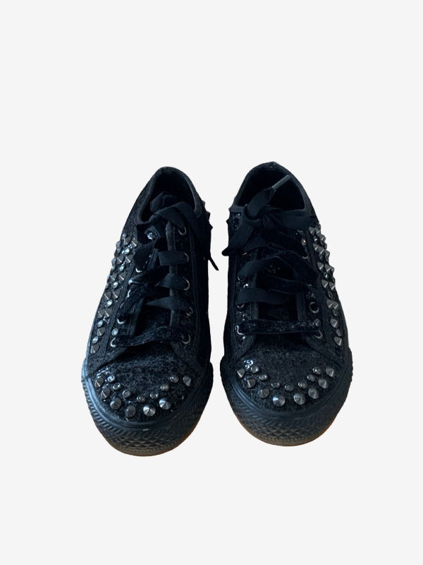 A pair of black low-top lace-up sneakers embellished with silver rhinestones around the eyelets and toe caps, shown from a top-down view on a light gray background.
