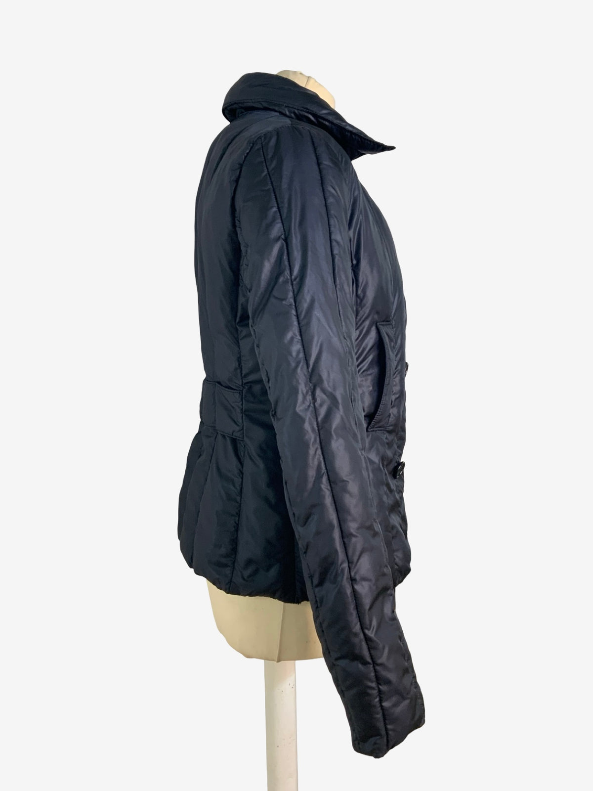 A black quilted puffer jacket displayed on a beige mannequin torso against a plain white background.