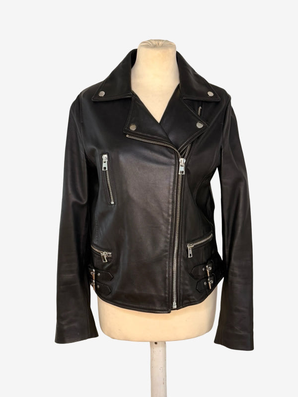 A black leather moto jacket with silver zippers and snap details, displayed on a beige mannequin torso against a light gray background.