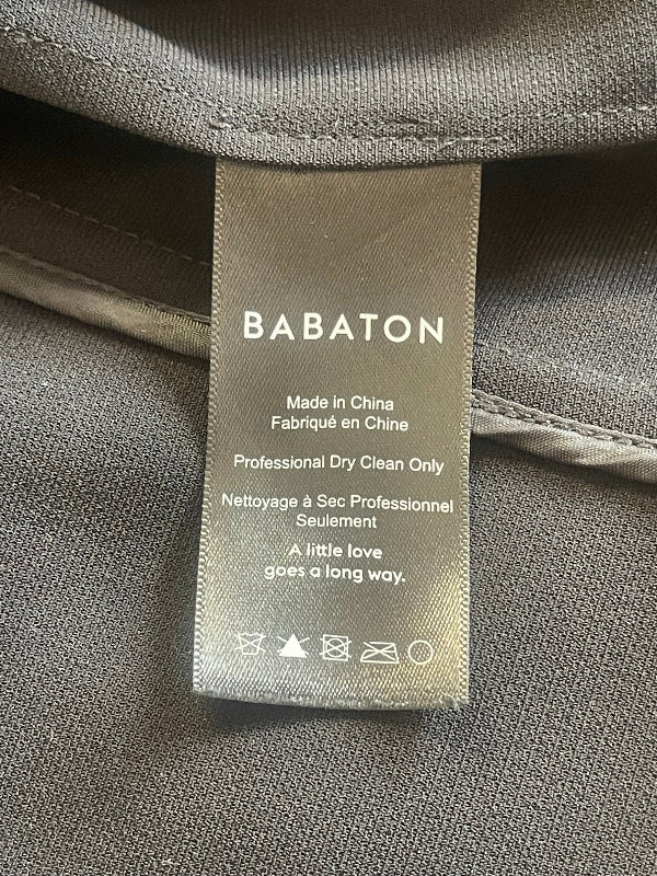 A close-up of a BABATON garment care label sewn onto a gray textured fabric, showing the brand name and care instructions.