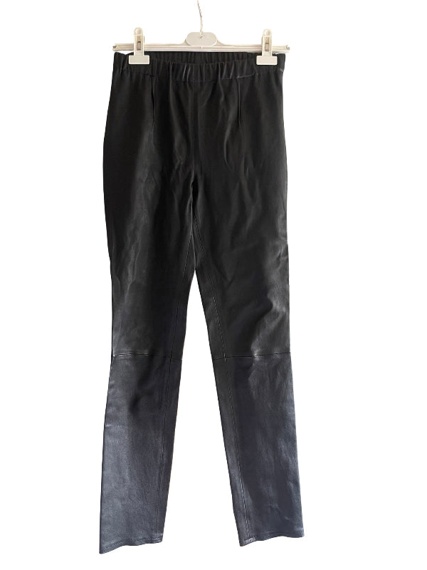 Black narrow leg trousers with a gathered elastic waistband, hanging from a white plastic hanger against a plain white background.