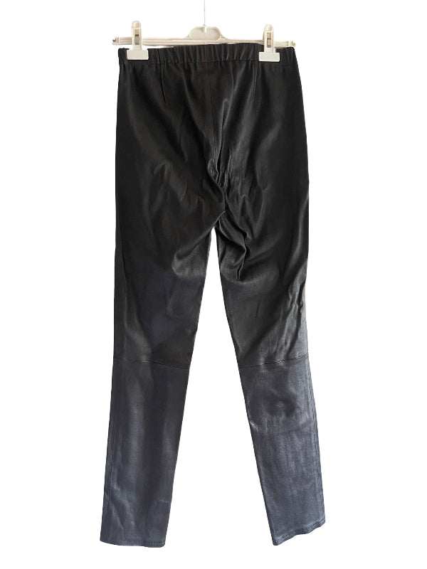 Black narrow leg pants with an elastic waistband, hanging from a white plastic hanger against a plain white background.
