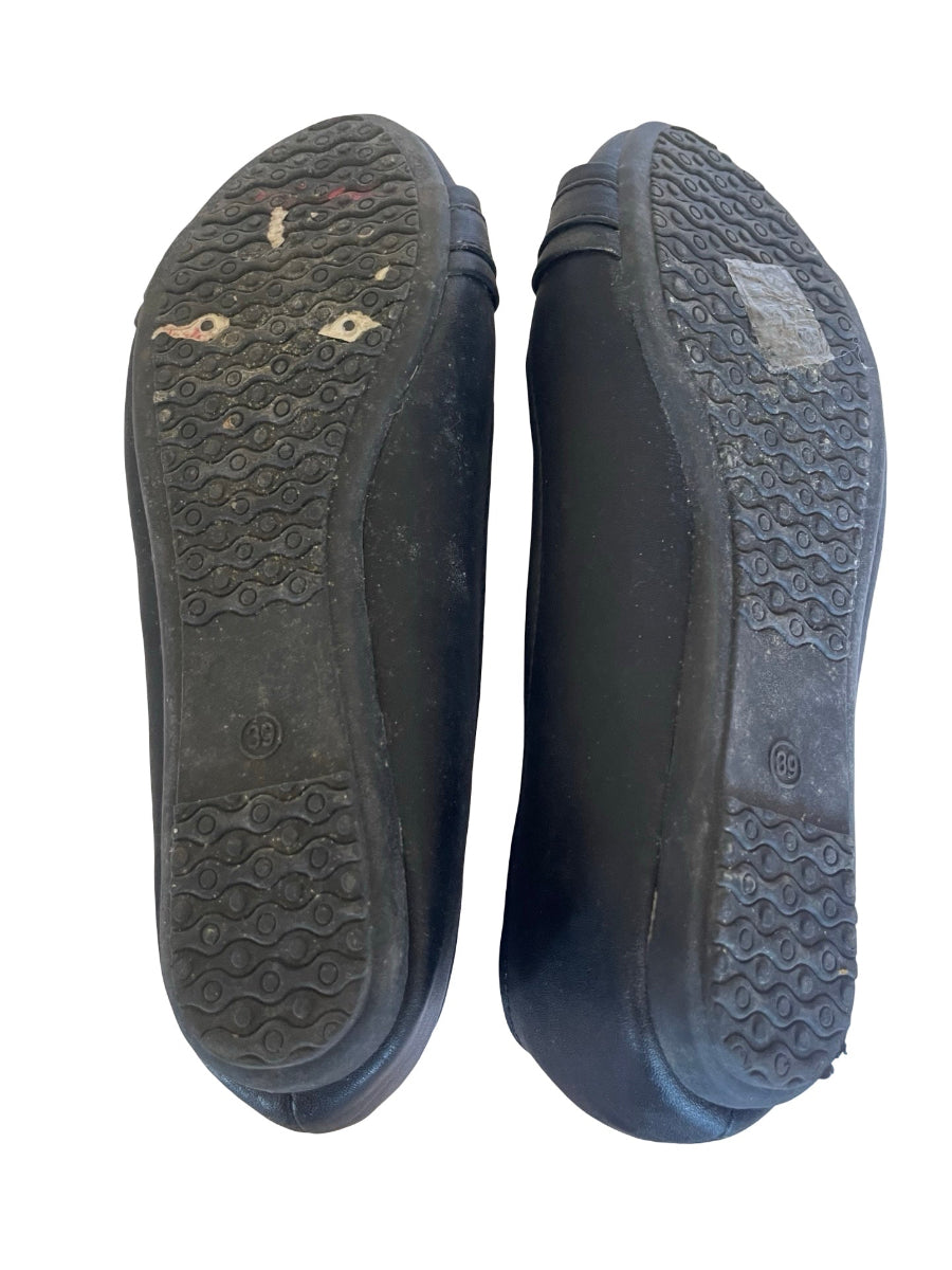 A pair of black rubber shoes or boots shown from the sole side, displaying the tread patterns and some visible dirt and scuffs on a plain white background.