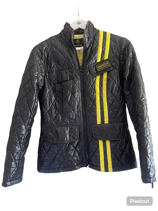 A quilted black leather jacket with two vertical yellow stripes on the right side and a black Barbour patch on the chest, hanging on a white hanger against a white background.