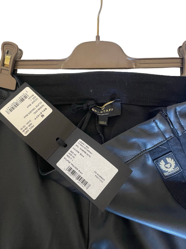Black leather pants from Belstaff hanging on a gray hanger, showing the waistband, interior label, price tag, and a small brand patch on the leg.