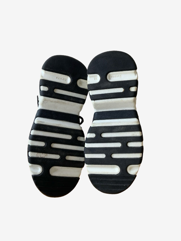 A pair of black and white athletic sneakers shown from the sole view, featuring a striped cushioned design, photographed against a light gray background.