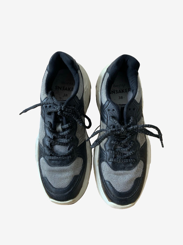 A pair of black and gray mesh sneakers with black laces, shown from a top-down view on a light gray background.