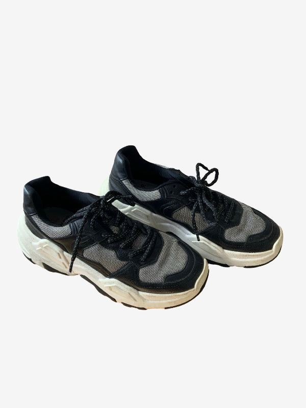 A pair of chunky low-top sneakers in black and gray mesh with thick off-white soles, displayed on a light gray background.