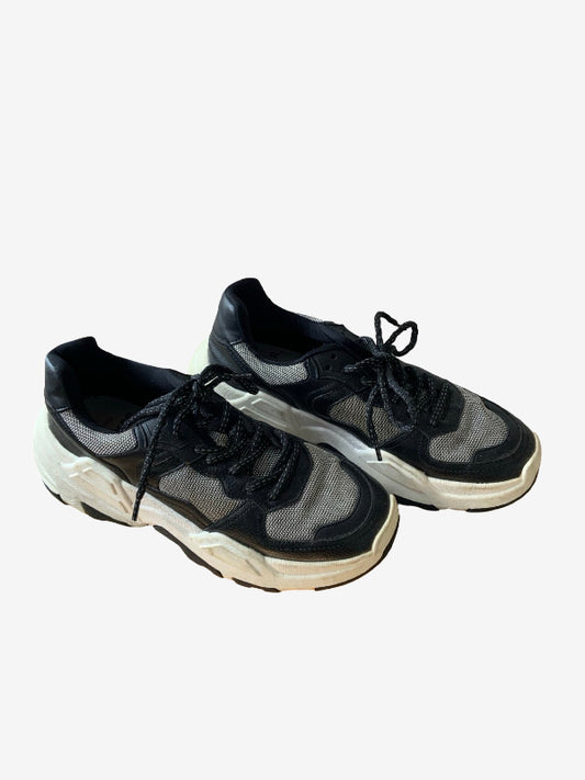 A pair of chunky low-top sneakers in black and gray mesh with thick off-white soles, displayed on a light gray background.