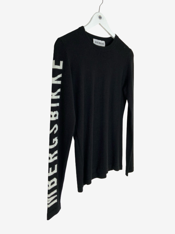 A black long-sleeve knit top hanging on a white hanger against a light gray background, featuring large white vertical text reading 'Biikenberg' down one sleeve.