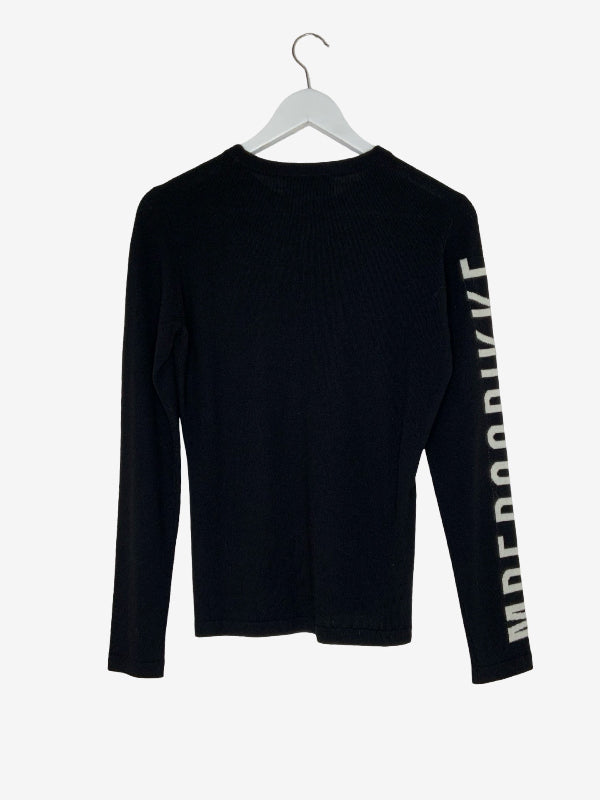 A black long-sleeve crewneck shirt hanging on a white hanger against a light gray background, featuring vertical white text on the right sleeve that reads 'BIKKENBERG'.