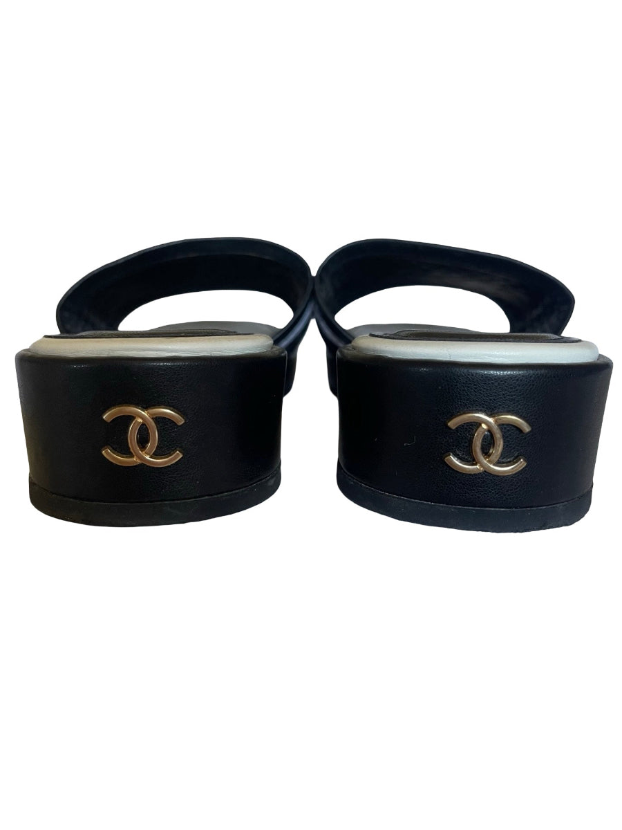A pair of black leather Chanel platform sandals with gold-tone interlocking CC logos on the platform heels, shown against a plain white background.