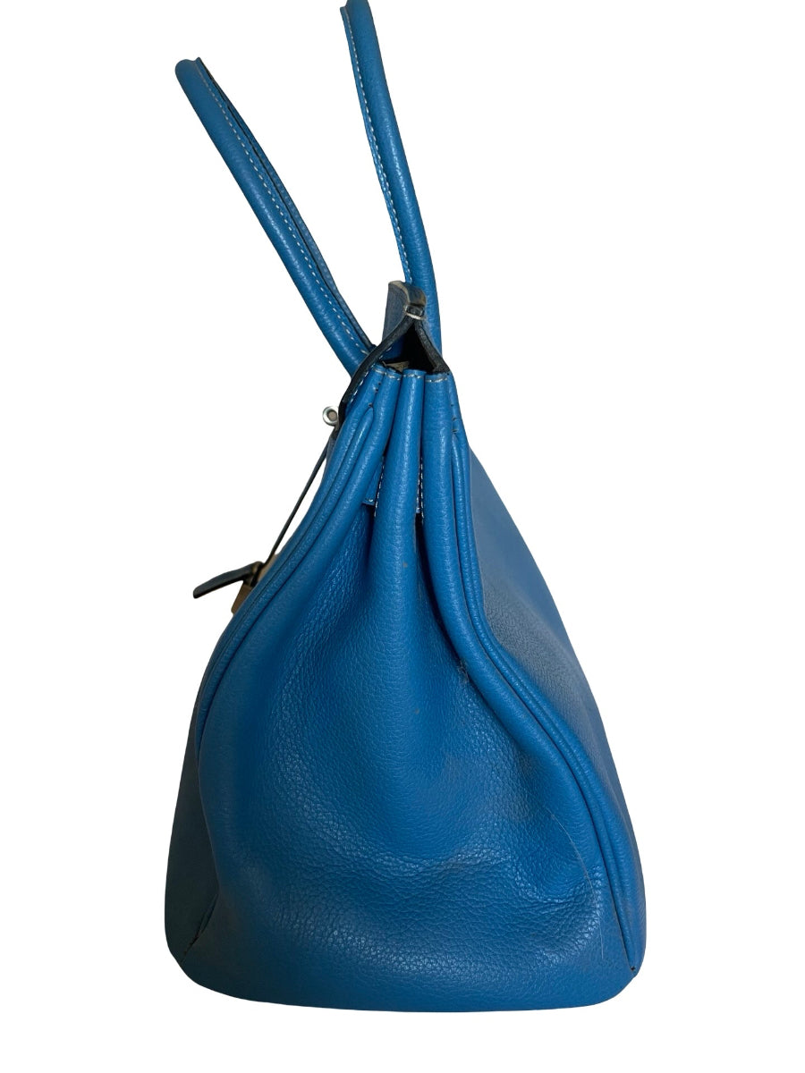 A blue pebbled leather slouchy shoulder bag with a drawstring top and long shoulder straps, shown against a plain white background.
