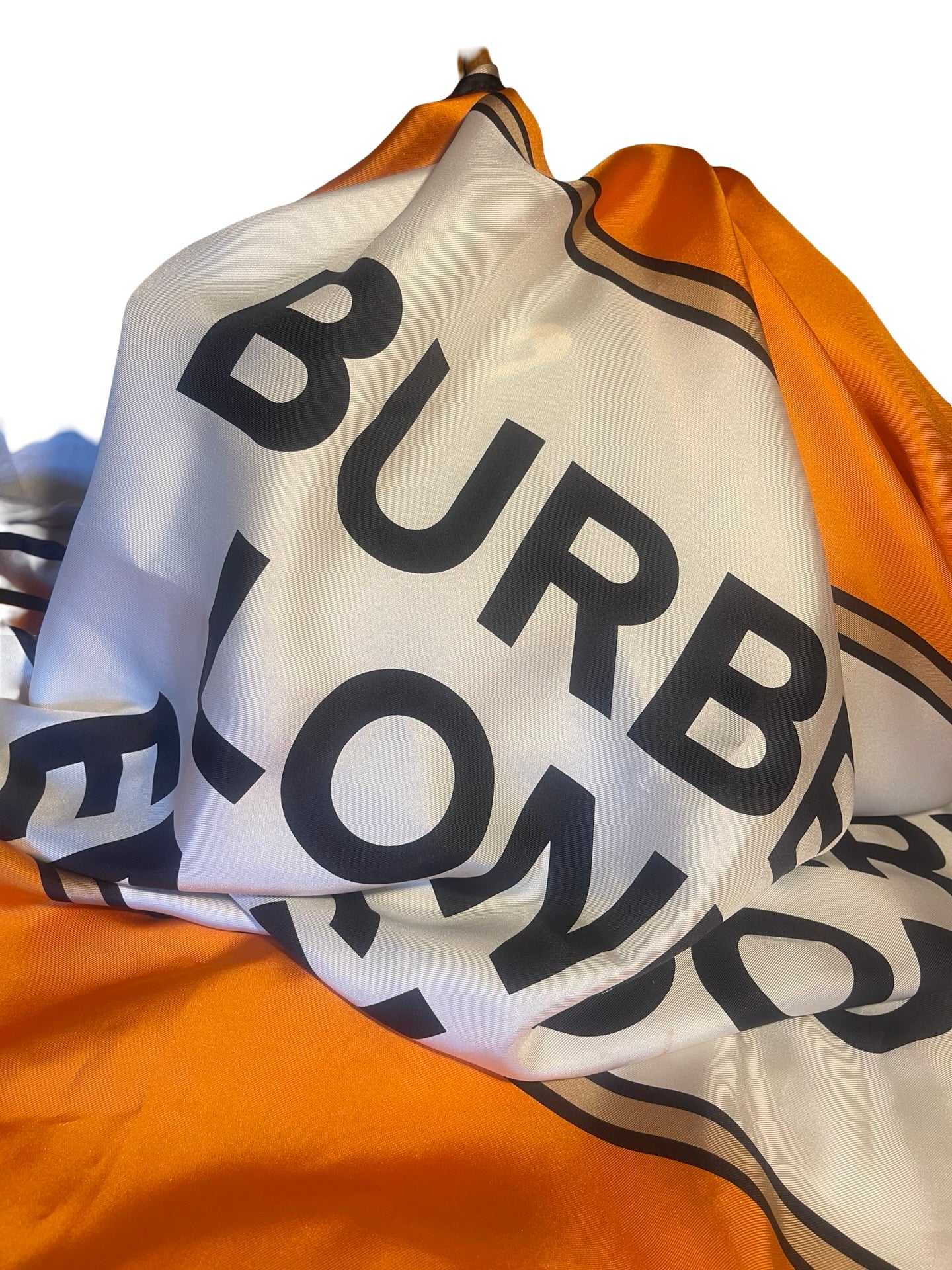 A close-up of a Burberry London scarf draped to show its signature orange and white color block design with black lettering.
