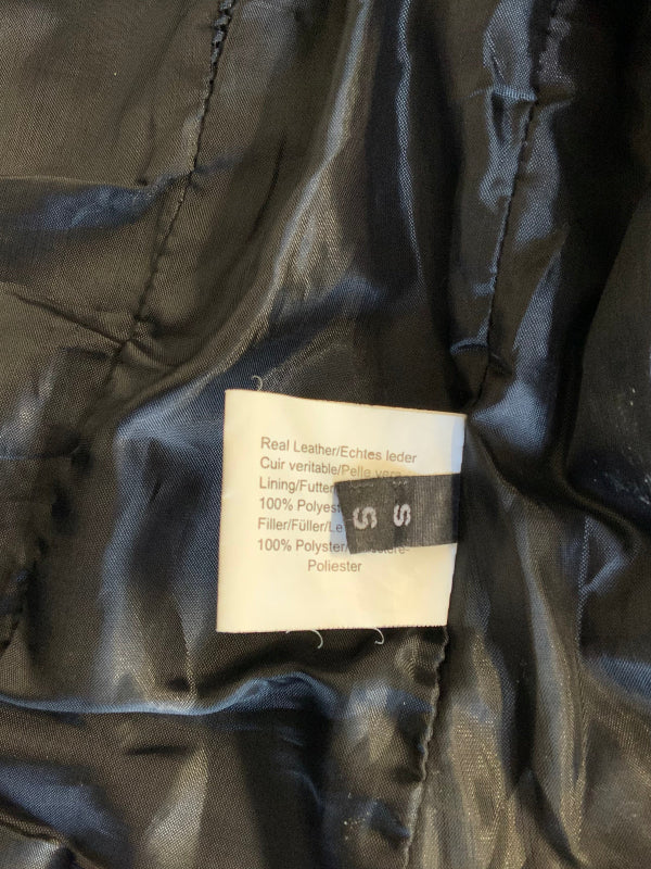 Close-up of a black leather jacket interior showing a sewn-on product label with text including 'Real Leather/Echtes Leder' and '100% Polyester'.