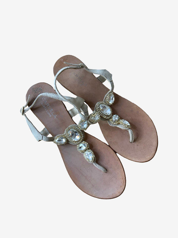 A pair of women's flat thong sandals with metallic silver straps adorned with clear rhinestones and crystals, set against a plain light gray background.