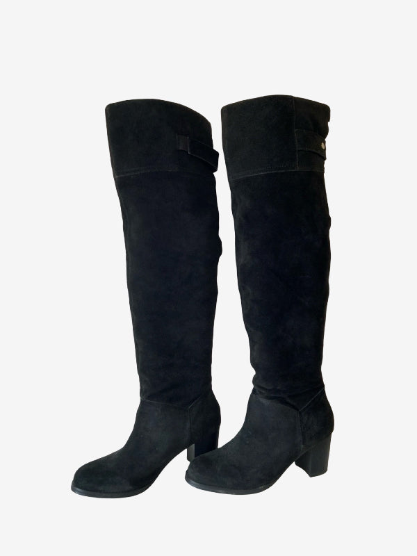 A pair of black suede over-the-knee boots with block heels and decorative strap details near the top, shown against a plain white background.