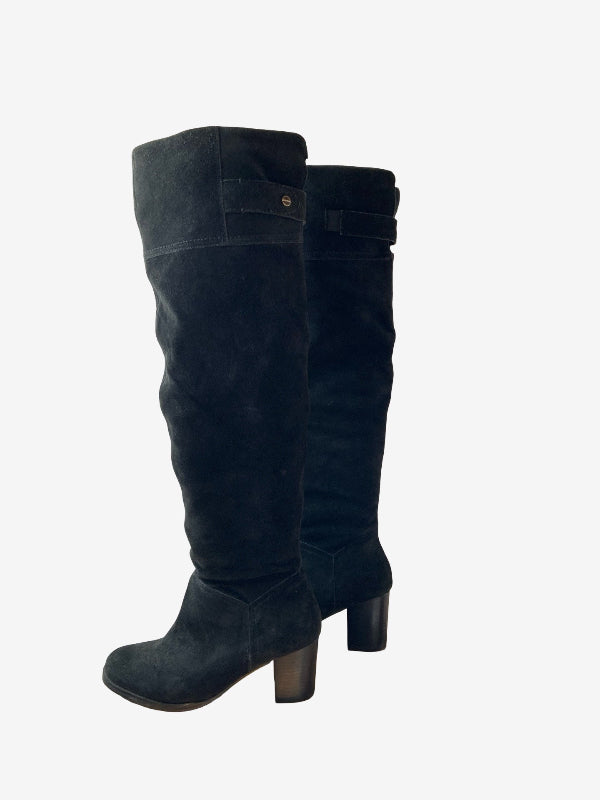 A pair of tall, knee-high black suede boots with block heels, shown from a side profile view against a plain white background.