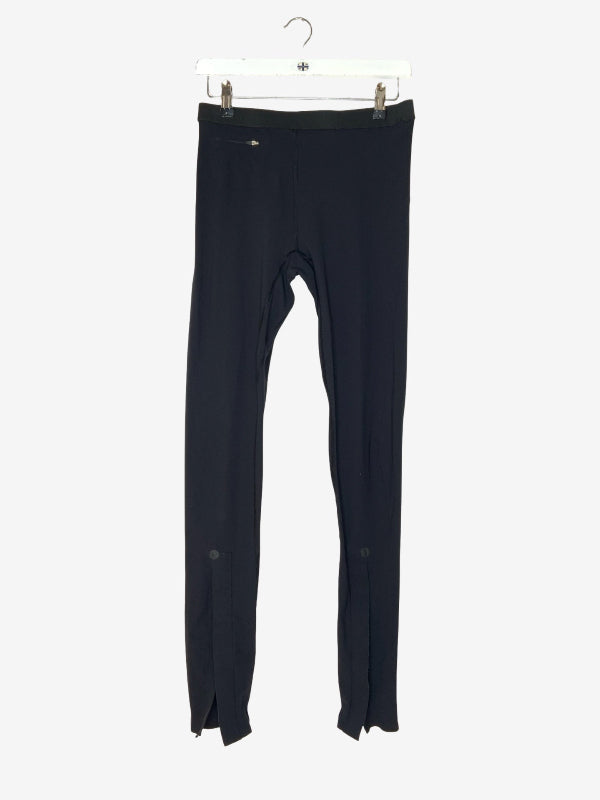 Black full-length leggings hanging from a white plastic hanger against a light gray background.