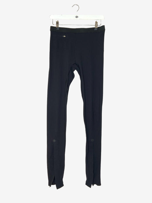 Black full-length leggings hanging from a white plastic hanger against a light gray background.