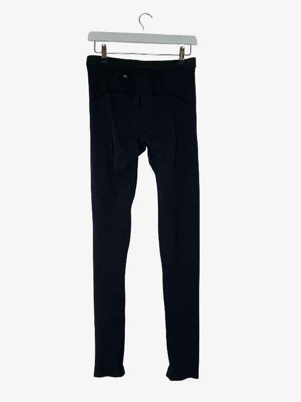 A pair of black slim-fit pants hanging from a white plastic hanger against a light gray background.
