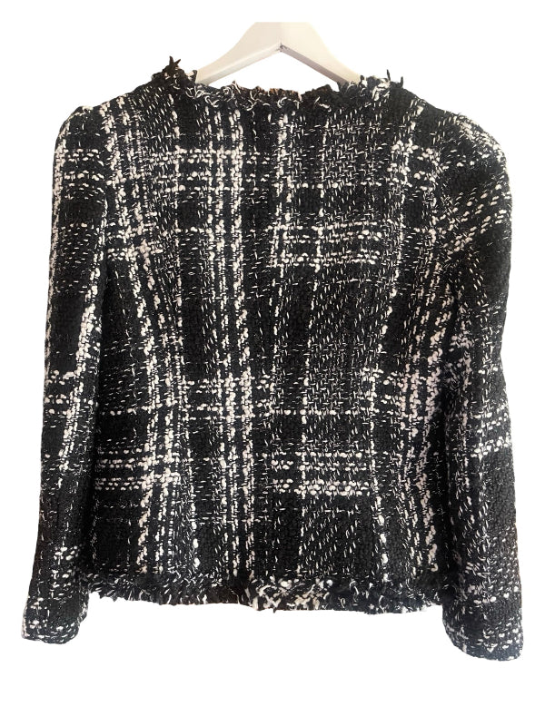 A black and white tweed plaid cropped jacket with long sleeves and frayed edges, hanging on a white hanger against a white background.