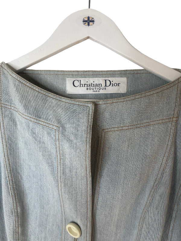 A light blue denim jacket hanging on a white wooden hanger with a Christian Dior label visible at the collar.
