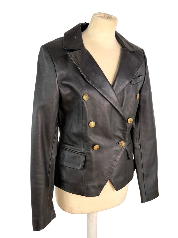 A black leather double-breasted blazer jacket with gold-tone buttons, displayed on a beige mannequin torso against a white background.