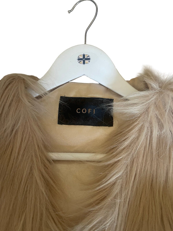 A close-up of a beige faux fur garment hanging on a white hanger with a visible Cofi brand label.