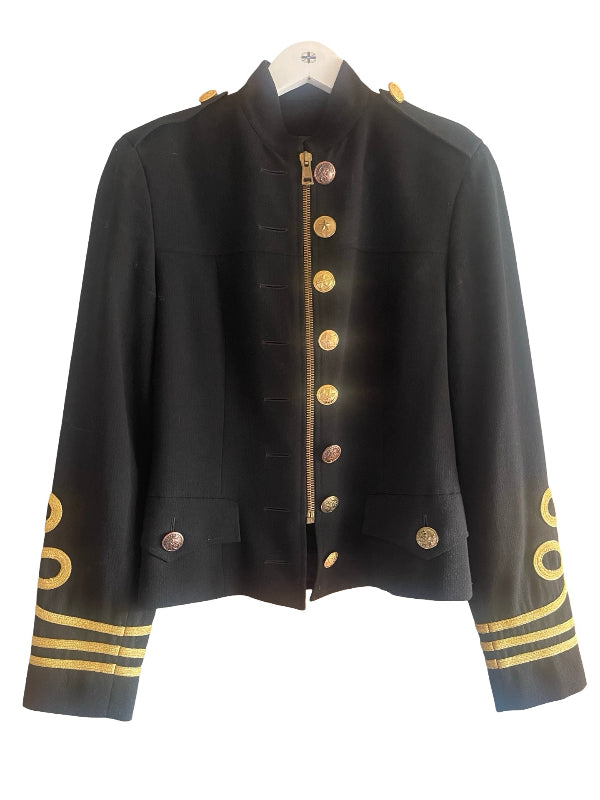A black military-style jacket with gold buttons, gold trim, and gold stripes on the cuffs, displayed on a white hanger against a white background.