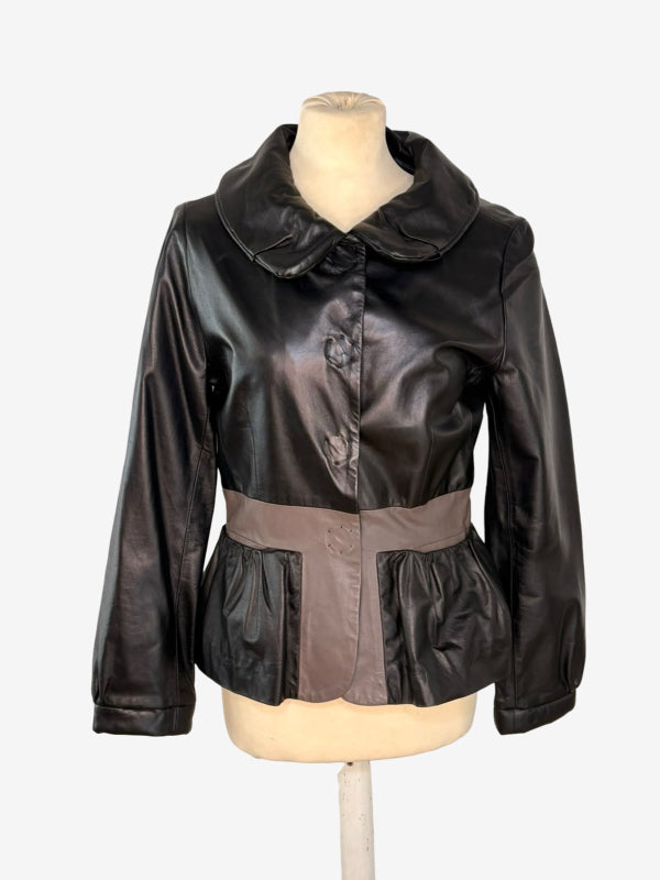 A black faux-leather jacket with a wide collar and button front, displayed on a cream mannequin torso against a light gray background.