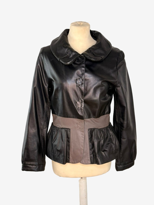 A black faux-leather jacket with a wide collar and button front, displayed on a cream mannequin torso against a light gray background.