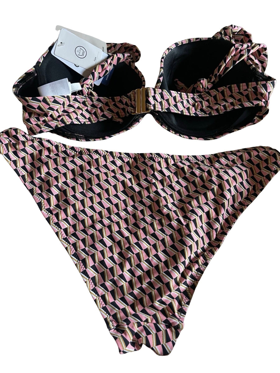 A two-piece bikini set with a geometric pattern in pink, black, and beige, featuring a plunge bra  top with a front knot and a matching high-cut bottom. The swimsuit is laid flat on a white background with a white paper tag attached to the top.