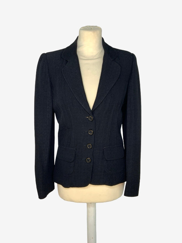 A black  tailored blazer with four front buttons, displayed on a cream-colored mannequin torso against a plain white background.