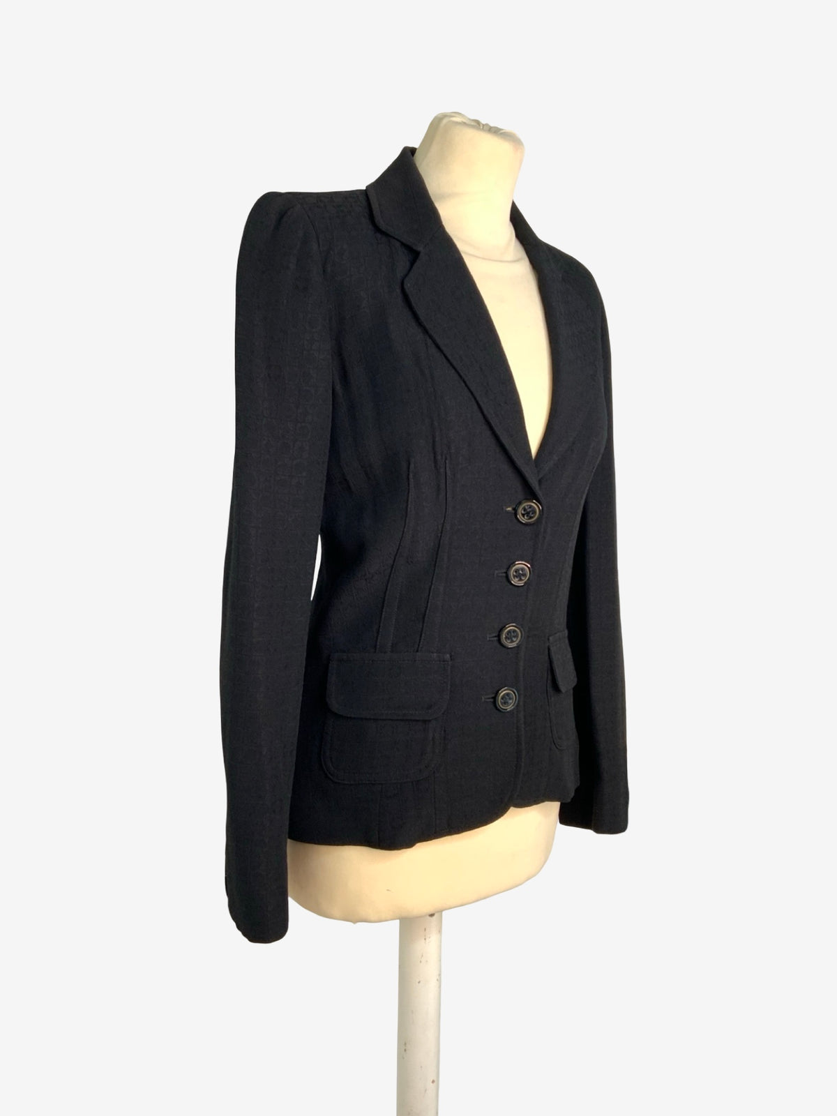 A black tailored blazer jacket displayed on a cream-colored mannequin torso against a light gray background.