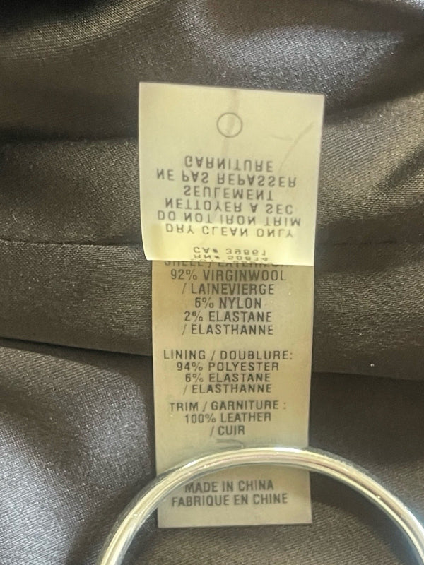 A close-up of a garment's interior tag showing fabric composition details in English and French, attached to a dark gray satin-like garment.